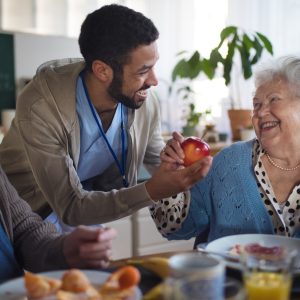 Smiling elderly woman and man enjoying breakfast in nursing home care center.